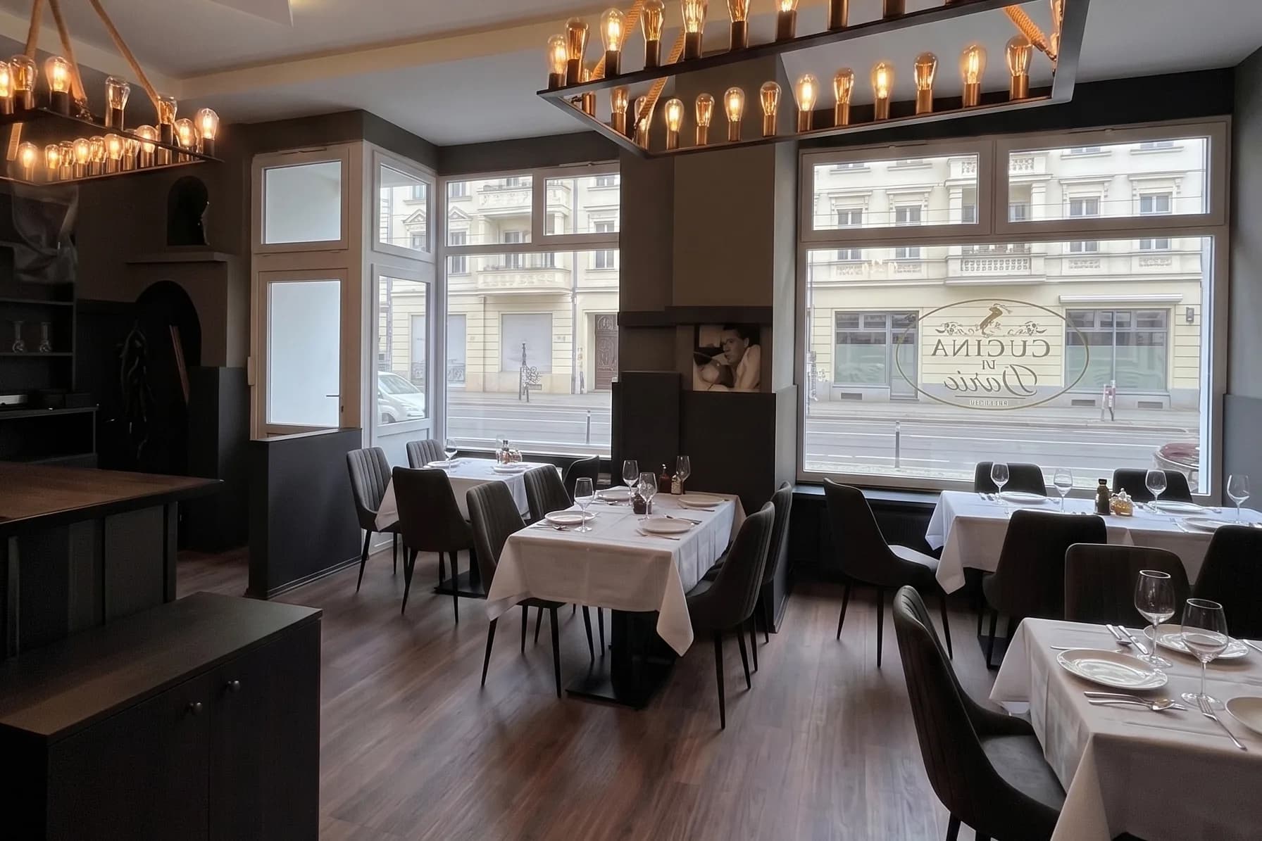Gastraum der Cucina di Dario mit eingedeckten Tischen, Glühbirnen-Kronleuchtern und der Fensterfront zur Neuen Kantstraße