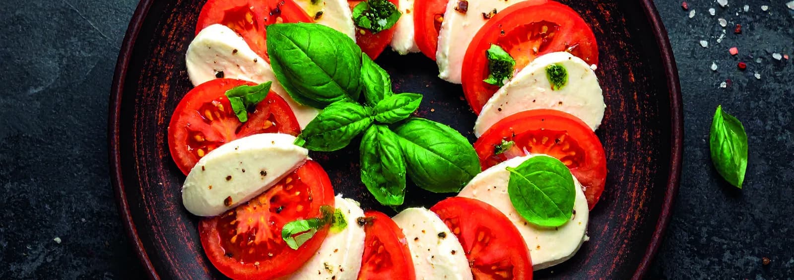 Mozzarella Caprese mit Tomatenscheiben und frischem Basilikum
