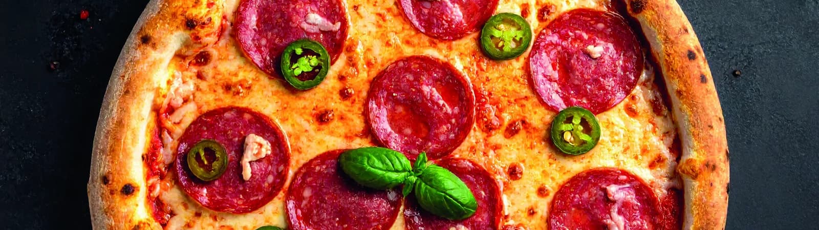Pizza mit Salami, Peperoni und Basilikum, frisch aus dem Ofen