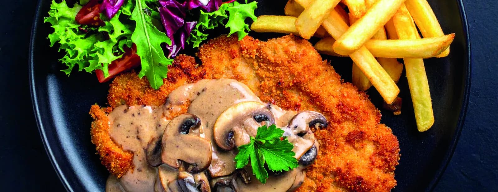 Paniertes Schnitzel mit Champignonrahmsauce und Pommes frites